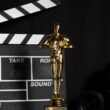 A golden trophy next to a film clapperboard symbolizes cinema success and achievement.