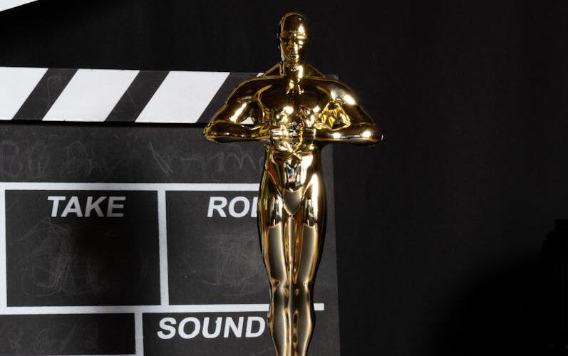 A golden trophy next to a film clapperboard symbolizes cinema success and achievement.