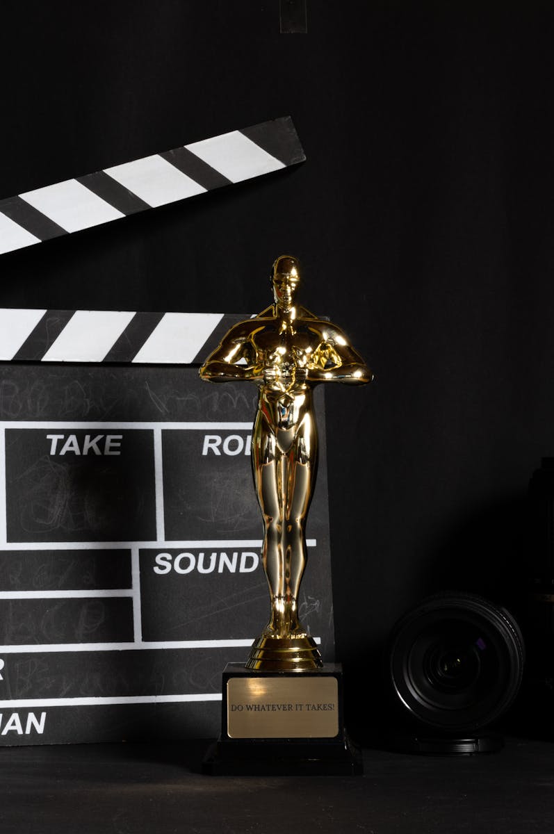 A golden trophy next to a film clapperboard symbolizes cinema success and achievement.