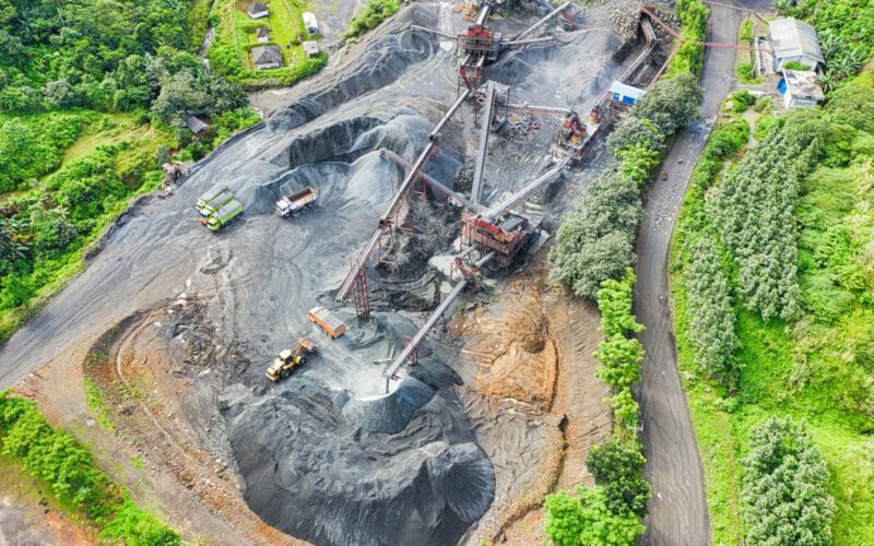 Aerial shot of a mining site surrounded by greenery, showcasing industrial activity.