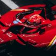 High-speed red racing car zooming down the track, showcasing logos and driver focus.