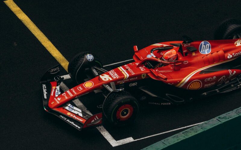 Dynamic shot of a red Formula One car racing on a track, showcasing speed and precision.