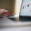 Person holding a credit card while shopping online on a laptop, indicating ecommerce transactions.