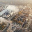 Aerial view showcasing an industrial complex in Poznań, Poland, emitting smoke and steam.