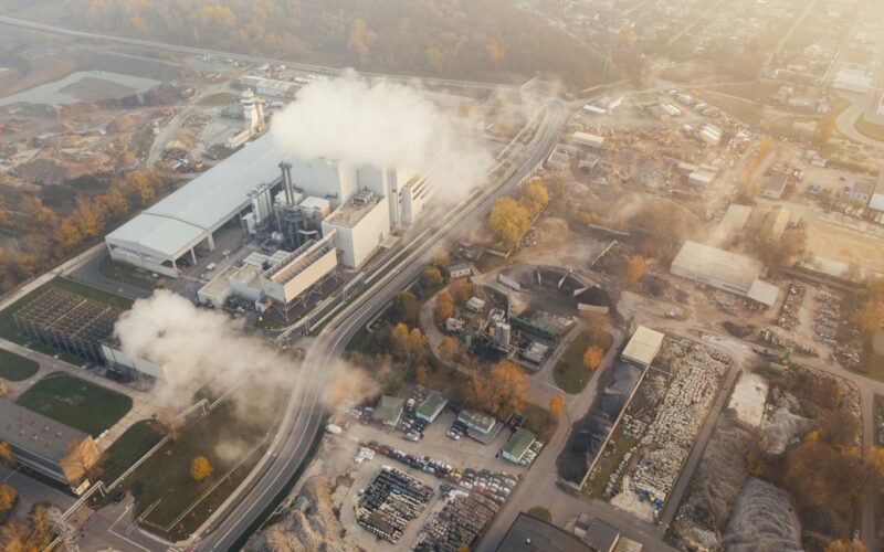 Aerial view showcasing an industrial complex in Poznań, Poland, emitting smoke and steam.