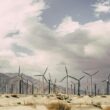 Wind turbines against dramatic desert landscape, promoting sustainable energy solutions.