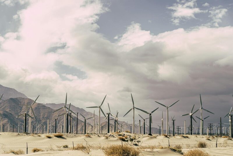 Wind turbines against dramatic desert landscape, promoting sustainable energy solutions.