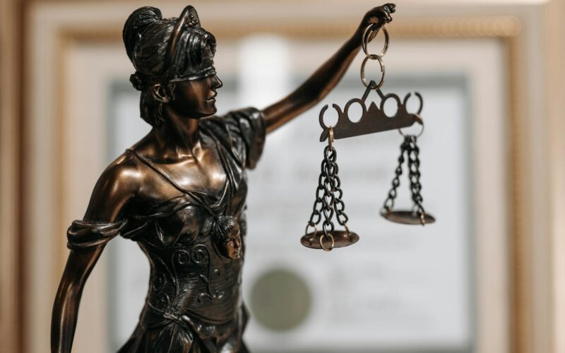 Close-up of a bronze Lady Justice statue holding scales in an office environment.