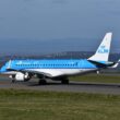 A KLM Cityhopper Embraer plane prepares for takeoff on a sunny day.