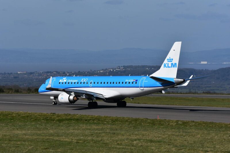 A KLM Cityhopper Embraer plane prepares for takeoff on a sunny day.