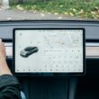 a person driving a car with a computer on the dashboard