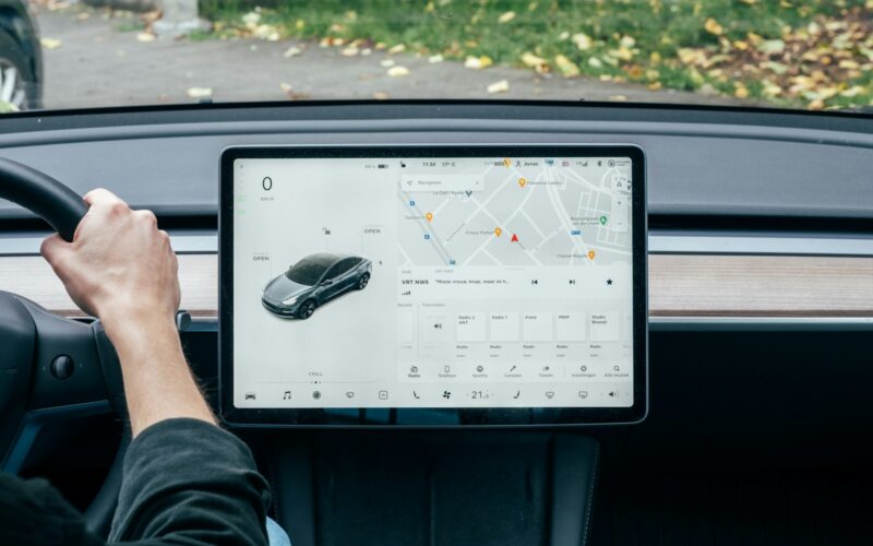 a person driving a car with a computer on the dashboard