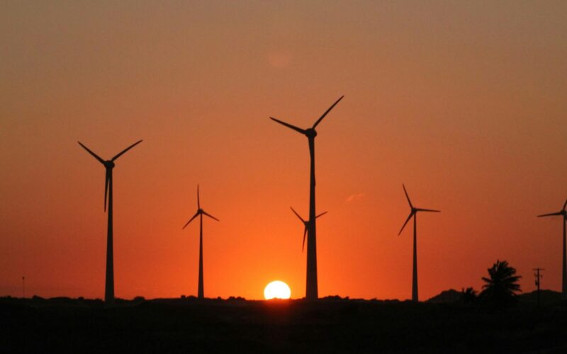 a group of windmills are silhouetted against a sunset