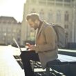 Barbat lucrând pe un laptop într-un parc