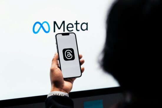 o persoana care tine in maman un telefon in fata unui ecran