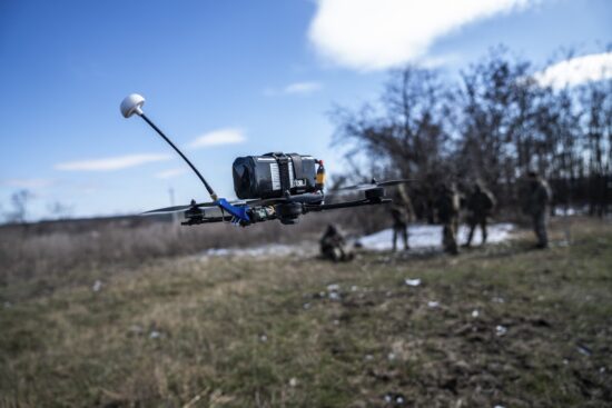 o drona pe campul de lupta cu niste soldati pe fundal