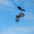 tom cruise in aer alaturi de o motocicleta pentru cascadorii de culoare neagra
