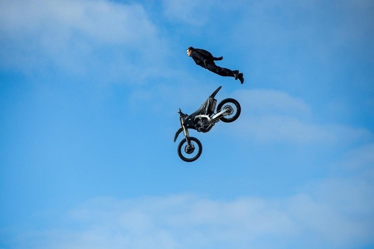 tom cruise in aer alaturi de o motocicleta pentru cascadorii de culoare neagra
