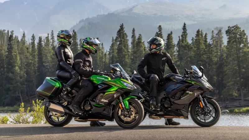 doua motociclete kawasaki la margine de drum muntos cu padure in spate