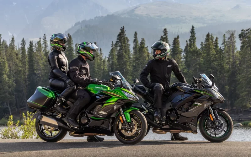 doua motociclete kawasaki la margine de drum muntos cu padure in spate