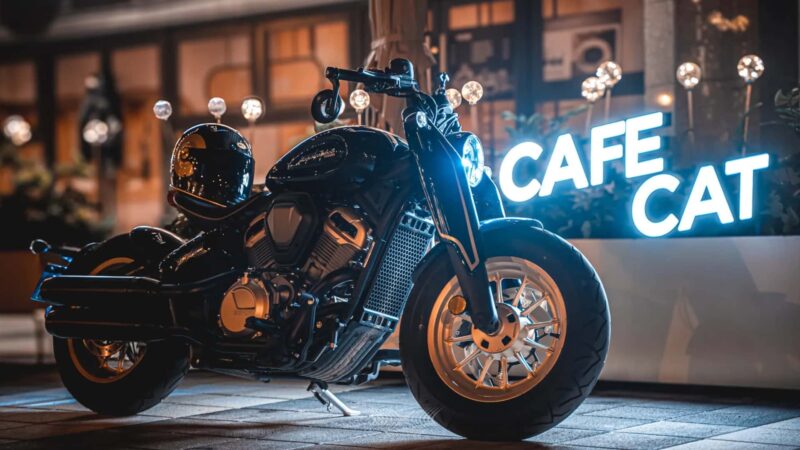 motocicleta benda de tipul chopper fotografiat in fata unei firme luminoase
