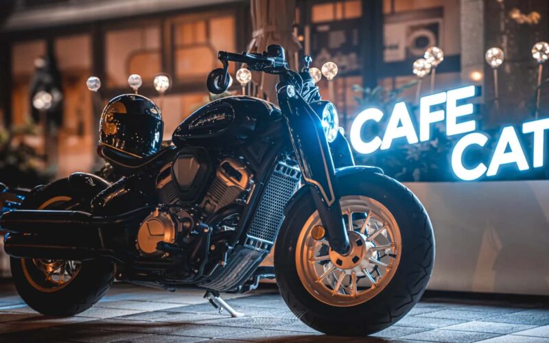 motocicleta benda de tipul chopper fotografiat in fata unei firme luminoase