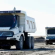 doua camioane miniere electrice si autonome deplasandu-se intr-o exploatare miniera
