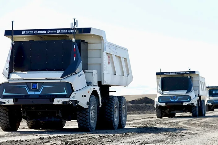 doua camioane miniere electrice si autonome deplasandu-se intr-o exploatare miniera