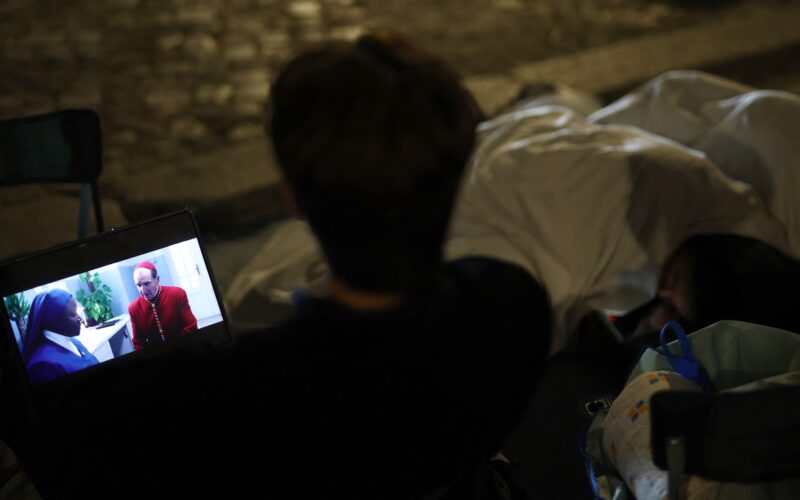 Un bărbat urmărește filmul "Conclave" pe laptopul său