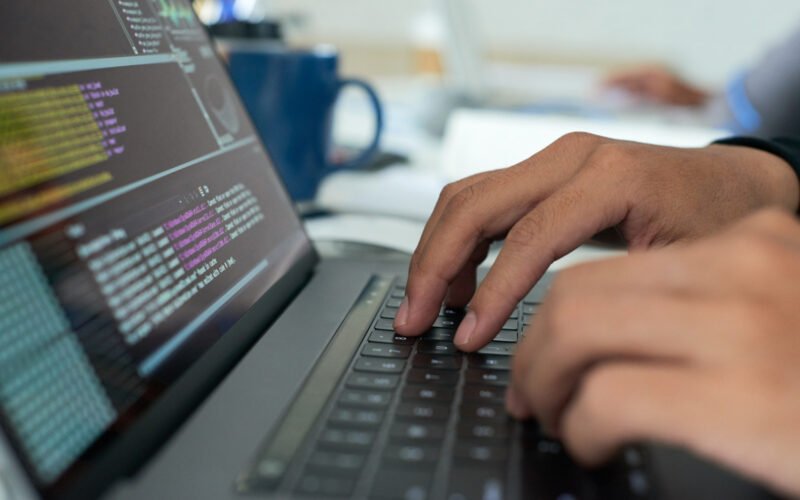 un programator scrie cod la un laptop