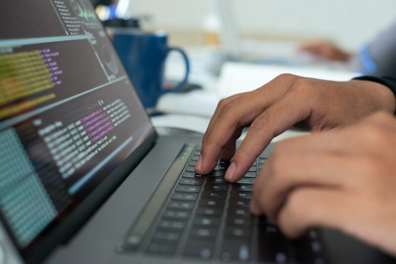 un programator scrie cod la un laptop