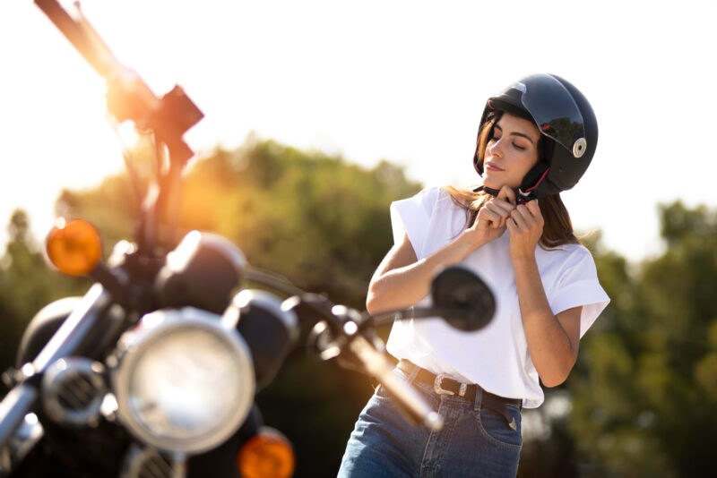 o femeie isi pune casca inainte de a se urca pe motocicleta