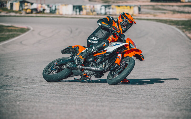 motocicleta ktm portocalie de tipul supermoto inclinata pe partea dreapta pe circuit