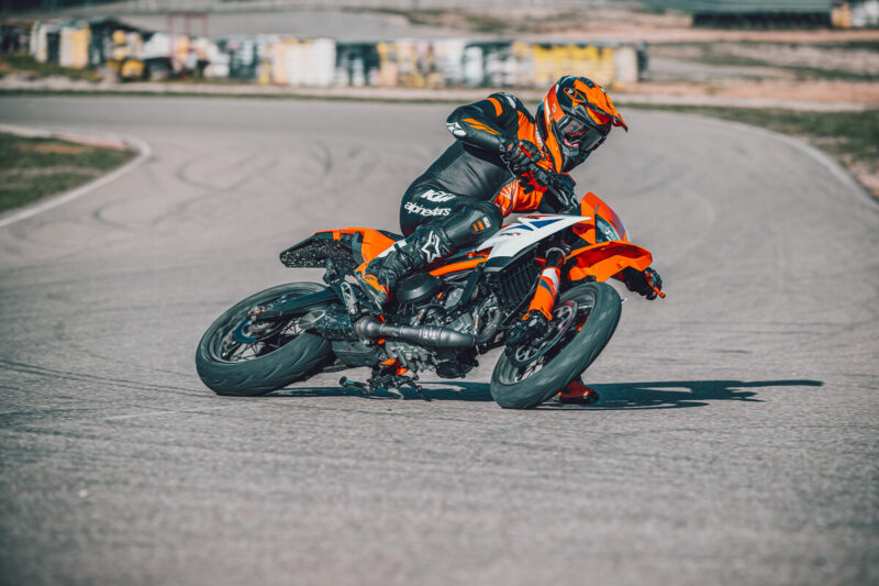 motocicleta ktm portocalie de tipul supermoto inclinata pe partea dreapta pe circuit