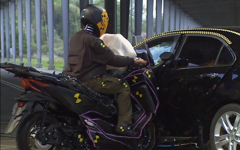 impact intre o motocicleta si o masina neagra intr-o hala de testare