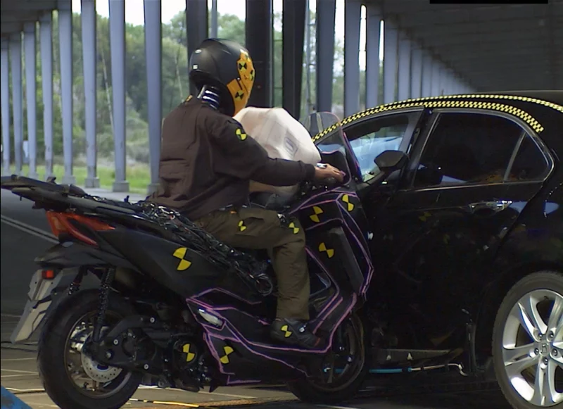 impact intre o motocicleta si o masina neagra intr-o hala de testare