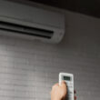 o femeie controleaza un aparat de aer conditionat