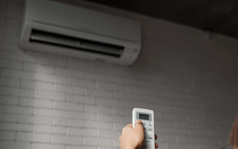 o femeie controleaza un aparat de aer conditionat
