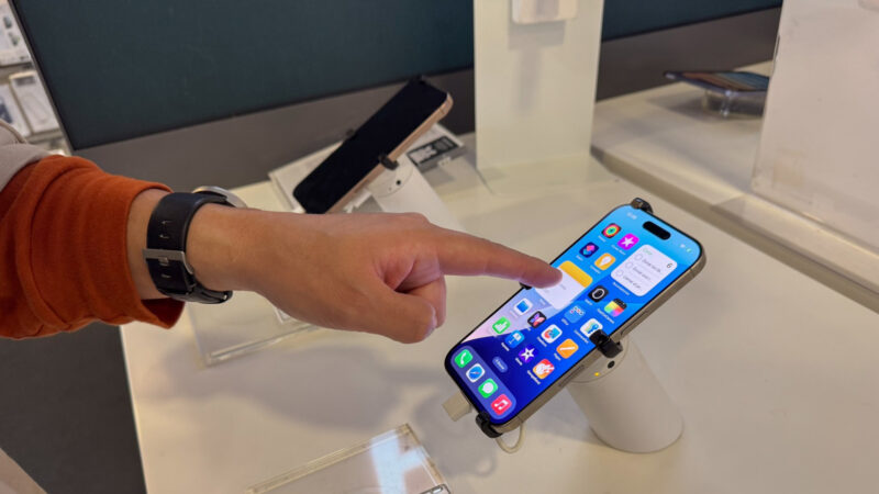un barbat testeaza un iphone intr-un magazin