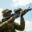 un soldat care tine in mana o arma echipata cu o luneta inteligenta care ajuta la doborarea dronelor