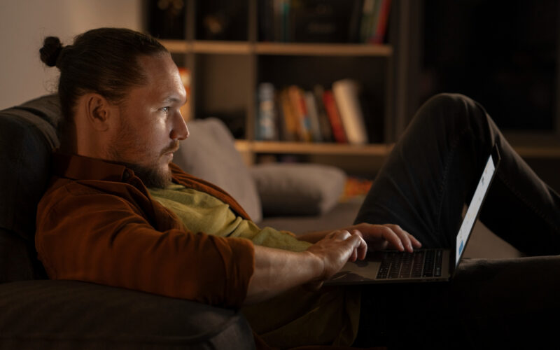 un barbat navigheaza pe internet folosind un laptop