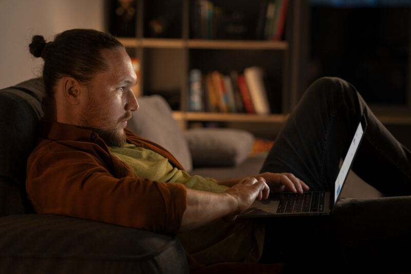 un barbat navigheaza pe internet folosind un laptop