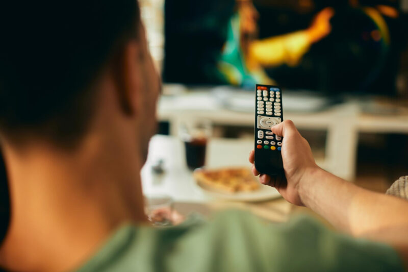 un barbat foloseste o telecomanda tv