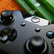 Xbox controller close-up with game cases on orange background.