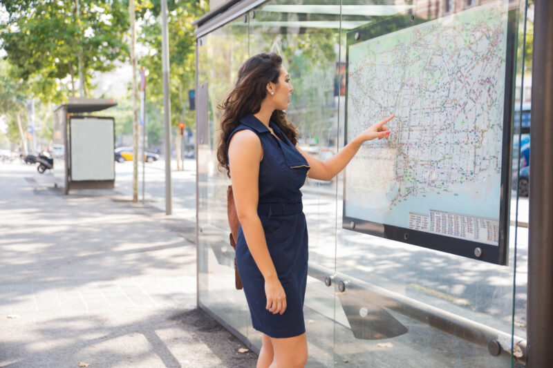 o femeie foloseste o statie de infromare intr-o statie de autobuz