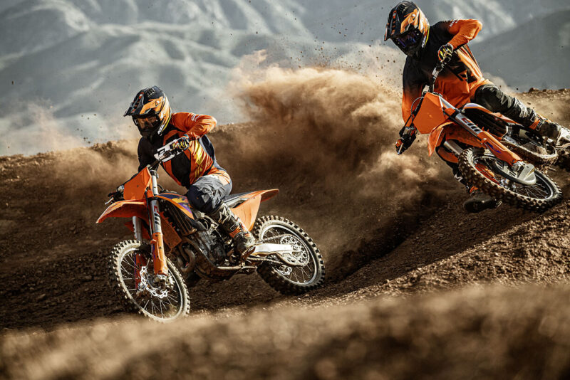 doua motociclete off road portocalii cu un munte in fundal