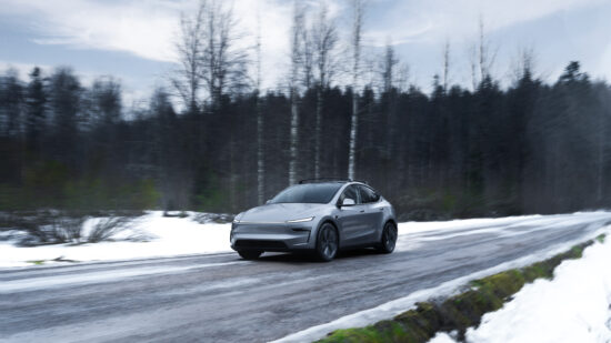Tesla Model Y conducând pe un drum acoperit de zapada