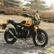 motocicleta galbena de tip scrambler adventure fotografiata la apus pe un teren accientat