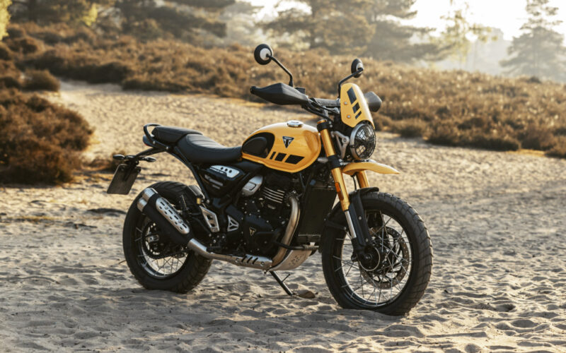 motocicleta galbena de tip scrambler adventure fotografiata la apus pe un teren accientat