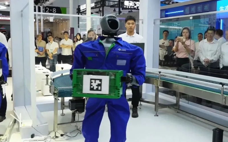 un robot industrial imbracat intr-o salopeta albastra tinand in maini o cutie verde